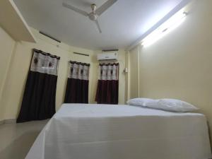 布莱尔港Amaravathi hotel and restaurant的卧室配有带窗帘的大型白色床