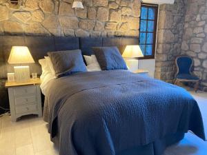 Les AssionsIdyllic French farmhouse的一间卧室配有一张蓝色的床、两张桌子和两盏灯。