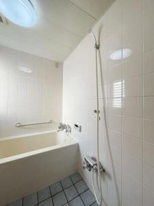 广岛bHOTEL M bld - Beautiful, spacious apartment next to Peace Park的设有带浴缸和淋浴的浴室。