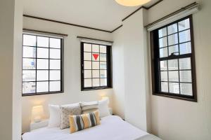 广岛bHOTEL Pacifica - 30sec walk to PeacePark, Beautiful Condo的一间卧室设有三扇窗户和一张带白色床单的床。