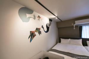 广岛bHOTEL Origaminn 402 - 5 mins PeacePark的一间卧室配有一张床,墙上挂着一些绘画作品