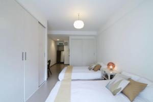 广岛bHOTEL La-Shante - 5 mins walk to the PeacePark & 2BR 10 ppl #101的白色卧室配有两张床和一张桌子