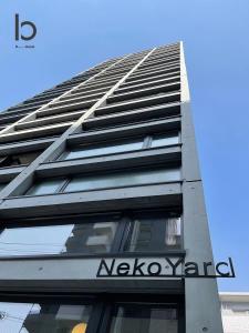 广岛bHOTEL Nekoyard - 1BR Apartment, Good for 6 Ppl, Near Peace Park, WIFI Available的一座高大的建筑,旁边有一个标志