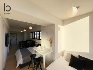 广岛bHOTEL Nekoyard - Lovely 1 BR Apartment, Very Near Peace Park, for 6Ppl的一间卧室配有一张床、一张桌子和一张沙发