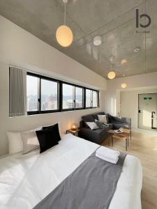 广岛bHOTEL Nekoyard - NEW 1 BR Apartment, Near Peace Park, Good 6Ppl的卧室配有一张白色的大床和一张沙发。