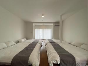 吴市bLOCAL Sugawa House - 1 Bedroom House with Beautiful Ocean View for 12 Ppl的带大窗户的客房内的三张床