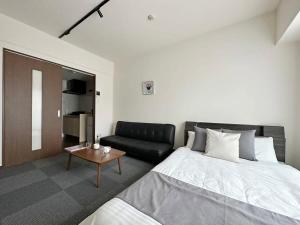 广岛bHOTEL Nagomi - Comfy Apartment for 3 people near City Center的一间卧室配有一张床和一张沙发