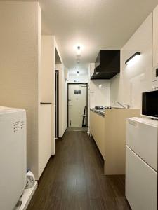 广岛bHOTEL Nagomi - Comfy Apartment for 3 people near City Center的一间厨房,配有白色家电和长长的走廊