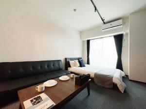 广岛bHOTEL Nagomi - Comfy 1 Bedroom in City Center for 3ppl的客房设有床、沙发和桌子。
