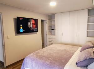 利马Apartamento en Miraflores con AC的卧室配有一张床,墙上配有电视。