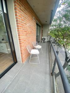 罗萨里奥Depto Genova, Zona Norte, Cochera disponible的阳台配有两把椅子和砖墙
