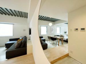 广岛bHOTEL Arts Dobashi - Cozy & Modern Studio Apt 5 Mins Walk to Peace Park的带沙发和镜子的客厅