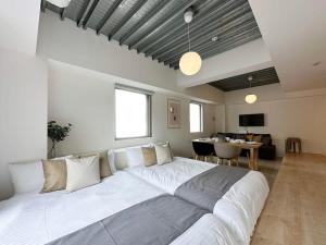 广岛bHOTEL Arts Dobashi - Cozy & Modern Studio Apt 5 Mins Walk to Peace Park的一张大白色的床,位于带桌子的房间