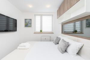 克拉科夫Sunny Kliny Apartment的白色卧室设有一张大床和一台平面电视。