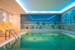 蒂门多弗施特兰德皇家酒店的一个带黄色椅子的游泳池和一个室内游泳池