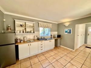 开普敦Charming Guest Suite in the Constantia Wine Valley的厨房配有白色橱柜和瓷砖地板。