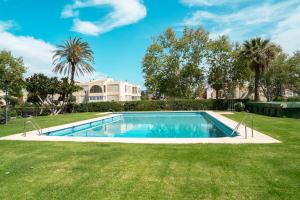 马拉加Sunstay - Seaview Guadalmar的一座位于庭院的游泳池,庭院里种着树木,房子里