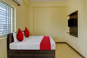 班加罗尔OYO Flagship Sri Chamundeshwari Boarding And Lodge的一间卧室配有一张带红色枕头的床和电视。