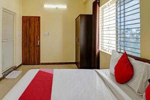 班加罗尔OYO Flagship Sri Chamundeshwari Boarding And Lodge的一间卧室配有一张带红色枕头的床和一扇窗户