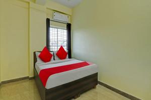 班加罗尔OYO Flagship Sri Chamundeshwari Boarding And Lodge的一间卧室配有一张带红色枕头的床和一扇窗户