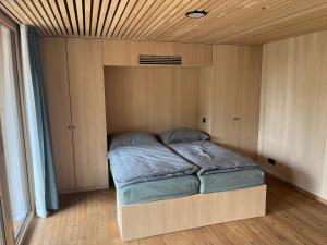 山麓布伦Tiny House Brunn am Gebirge的小型客房的一张床位,设有木制天花板