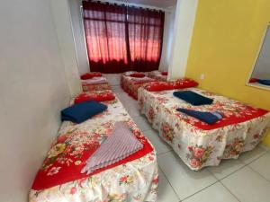 贝伦Hotel SANTA CLARA的配有红色床单和蓝色枕头的三张床