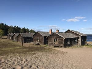 UlvöhamnSandvikens Fiskeläge Ulvön的海滩上一排古老的木屋