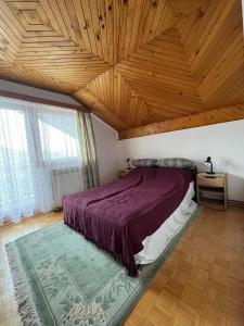 萨拉热窝Guesthouse Vratnik的一间卧室设有紫色的床和木制天花板