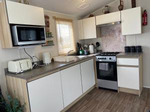 Littlestone-on-SeaComfy Cosy Caravan_Romney Sands的厨房配有白色橱柜和炉灶烤箱。