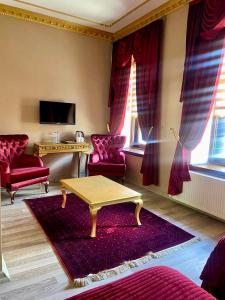 卡尔斯Hotel Katerina Sarayı 1877的客厅配有红色椅子和茶几
