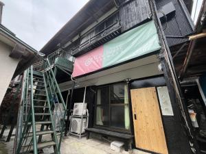 汤河原町温泉街の入り口にあるゲストハウス SLOW HOUSE yugawara的建筑的侧面有标志