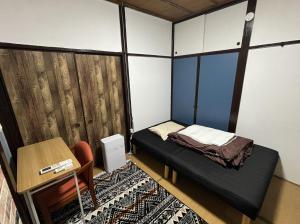 汤河原町温泉街の入り口にあるゲストハウス SLOW HOUSE yugawara的小房间设有一张小床和一张书桌