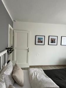 埃姆登Ferienwohnung Altstadtblick的白色的房间,设有一张床,墙上有三张照片