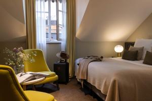 日内瓦Hotel D Geneva的酒店的客房 - 带一张床、椅子和窗户