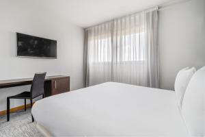 马德里Exe Convention Plaza Madrid的一间酒店客房,配有一张白色的床和一张书桌