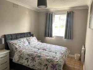 拉辛赫Lahinch Central 3-Bed Retreat的一间卧室配有一张带花卉棉被的床和窗户。