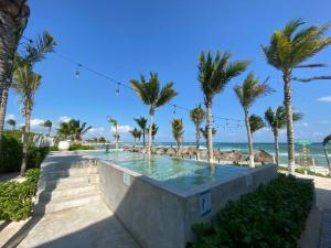 艾库玛尔Big 5BR Home for an epic time in Riviera Maya的棕榈树海滩旁的游泳池