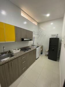 布卡拉曼加Sachar Lodging Apartahotel的厨房配有棕色橱柜和黑色冰箱