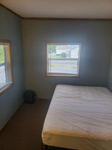 RockSpacious ATV Retreat House的卧室配有白色的床和2扇窗户。