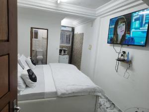 杜阿拉Chambre Meublée à Douala, Bonapriso - Armée del'air的卧室配有一张床铺,墙上配有电视