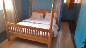 金贾Meral inn Jinja的一张带白色床单和枕头的木床