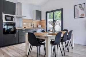 拉戈尔Maison T4 Climatisée avec Jacuzzi à Lagord的厨房配有带椅子的木桌