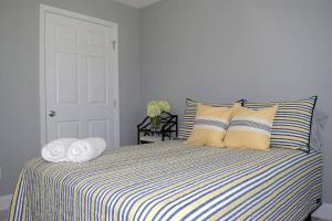圣奥古斯丁Secret Cottage 10 min to DT Dogs OK BBQ Parking的一间卧室配有带条纹床单和枕头的床
