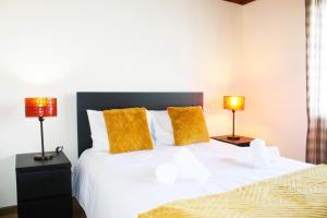 蓬塔德尔加达Vieira Rooms Natural Pools的一间卧室配有一张带两盏灯的大型白色床。