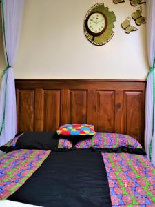 恩德培Lake Victoria Country Home的一张带木制床头板和墙上时钟的床