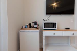 朗塞斯顿Cosy Accommodation Moments From The Centre Of Town with Wifi的一张带微波炉的桌子和一台墙上的电视