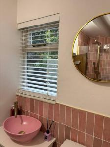 阿什伯恩Rosie Cottage的浴室设有粉红色的盥洗盆和镜子