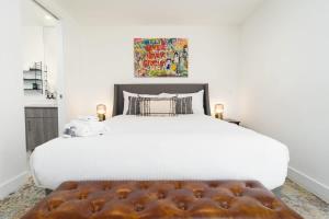 圣地亚哥Bright and Trendy 2-story Bankers Hill Condo的卧室配有一张白色大床和棕色的搁脚凳