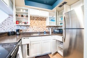卡萨格兰德78- Modern Casa Grande Desert Paradise heated pool的厨房配有白色橱柜和不锈钢冰箱