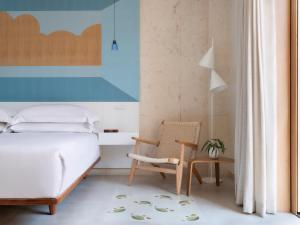 圣多明各Kimpton Las Mercedes, an IHG Hotel的一间卧室配有一张床和一把椅子